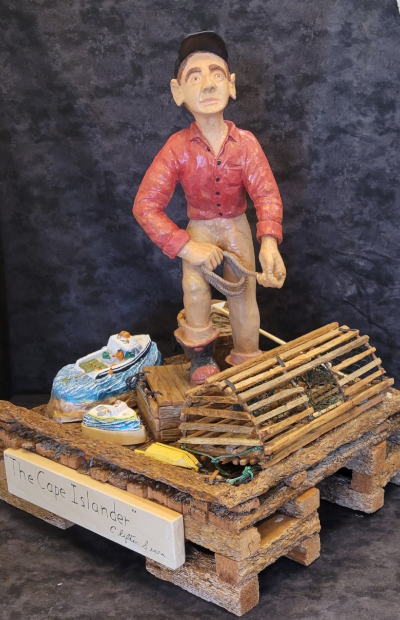 A carvng of a Cape Island fisherman on a wharf with small Cape Island boats.