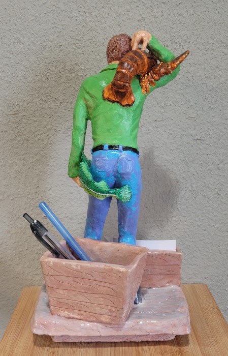 A fisherman is on a wharf, holding a lobster on his shoulder and a cod fish in his hand - rear view